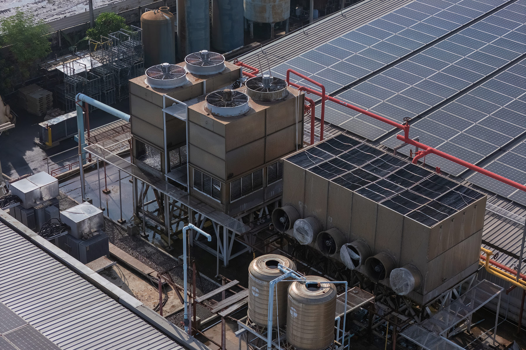 Aerial view of an industrial facility with cooling towers, storage tanks, piping networks, and rooftop solar panels, representing the type of manufacturing and processing environment where composite pressure vessels are used for CO₂, nitrogen, helium, and buffer-air gas storage and regulation.