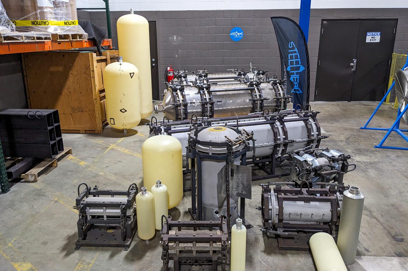 Various composite pressure vessel liners and prototypes in different stages of fabrication displayed in a workshop, illustrating Steelhead’s advanced manufacturing for hydrogen-compatible containment systems.