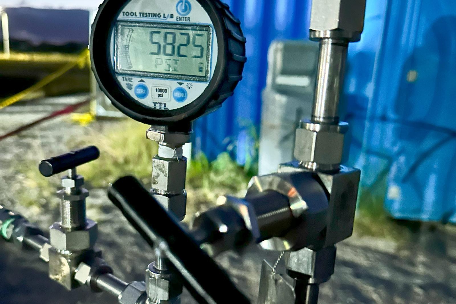 Close-up of a digital pressure gauge reading 5,825 psi on a HydrogenCube system, with stainless steel fittings and high-pressure valves in the foreground.