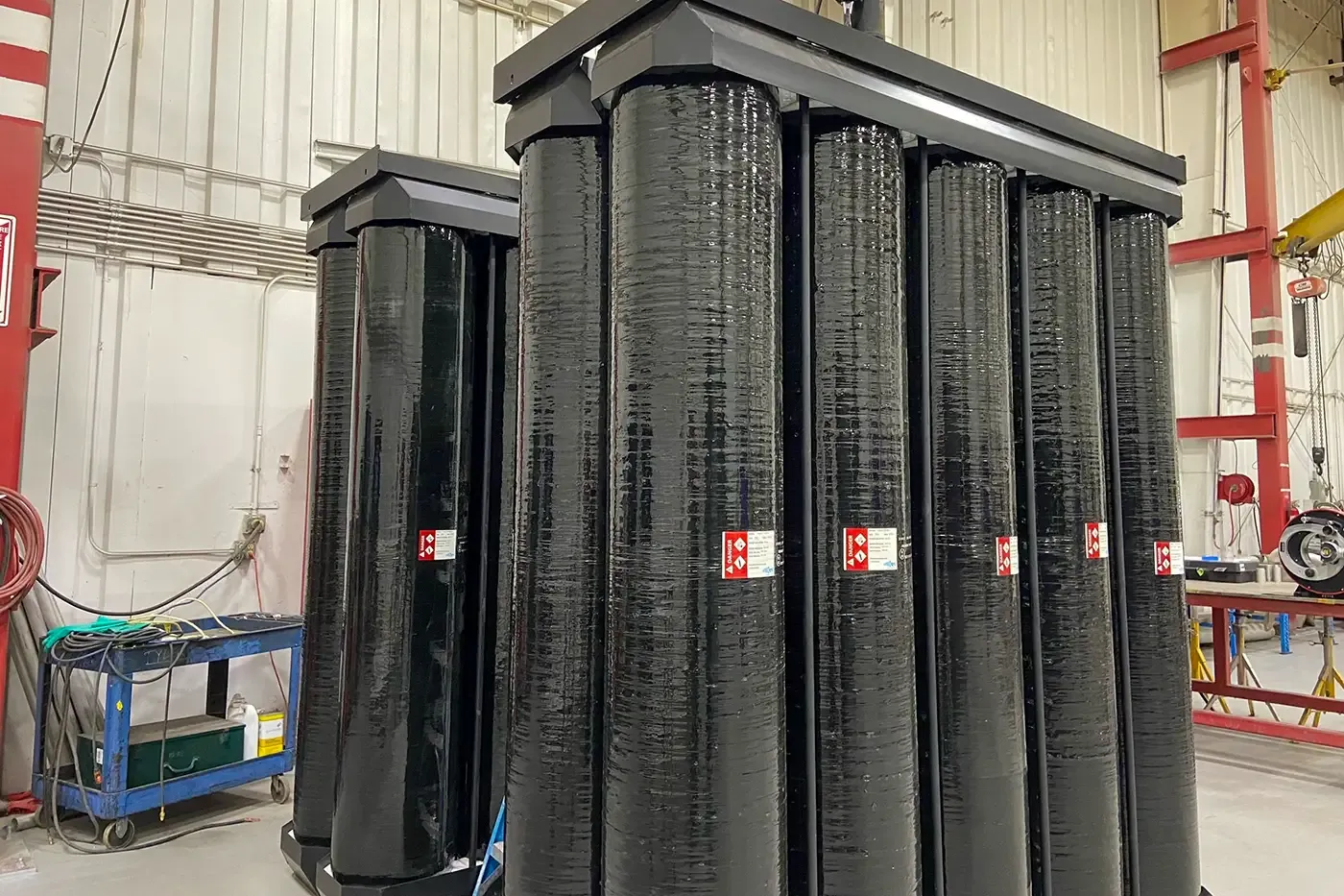 Vertical high-pressure composite gas vessels arranged in a rack system for stationary hydrogen energy storage at renewable energy or electrolyzer sites.