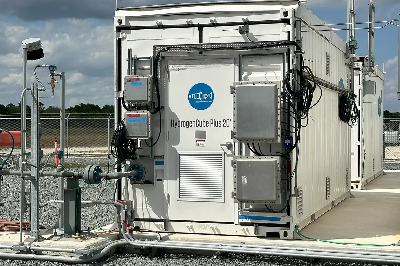 HydrogenCube Plus 20' container at a research facility, connected to piping and instrumentation, illustrating its use as buffer storage for steady-pressure hydrogen supply in lab and pilot-scale operations.