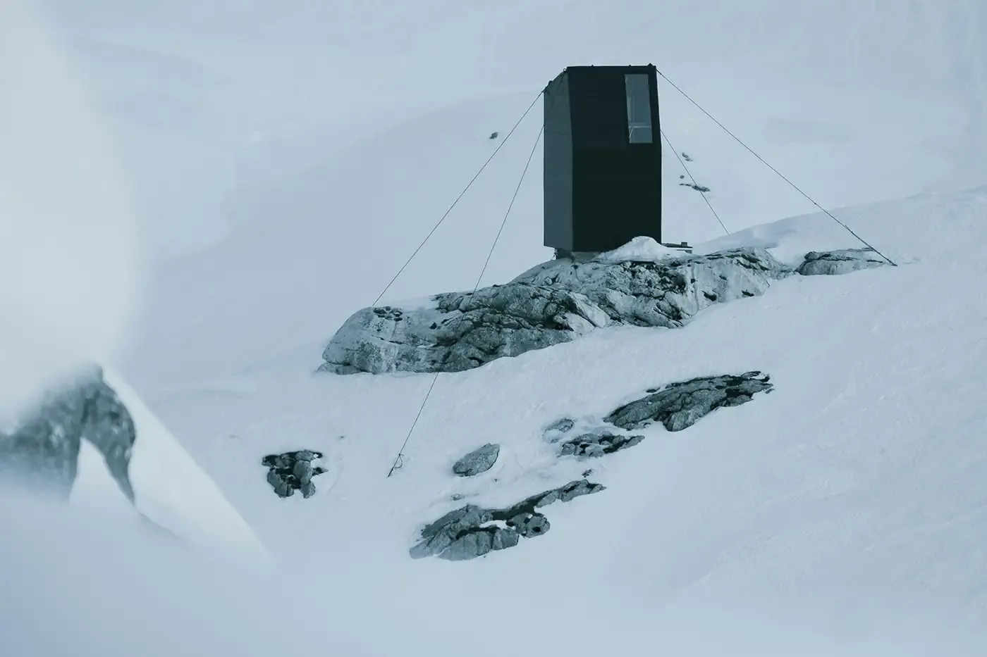 Isolated off-grid shelter in a snowy mountain environment, illustrating the need for mobile compressed gas delivery to support clean energy in remote locations.