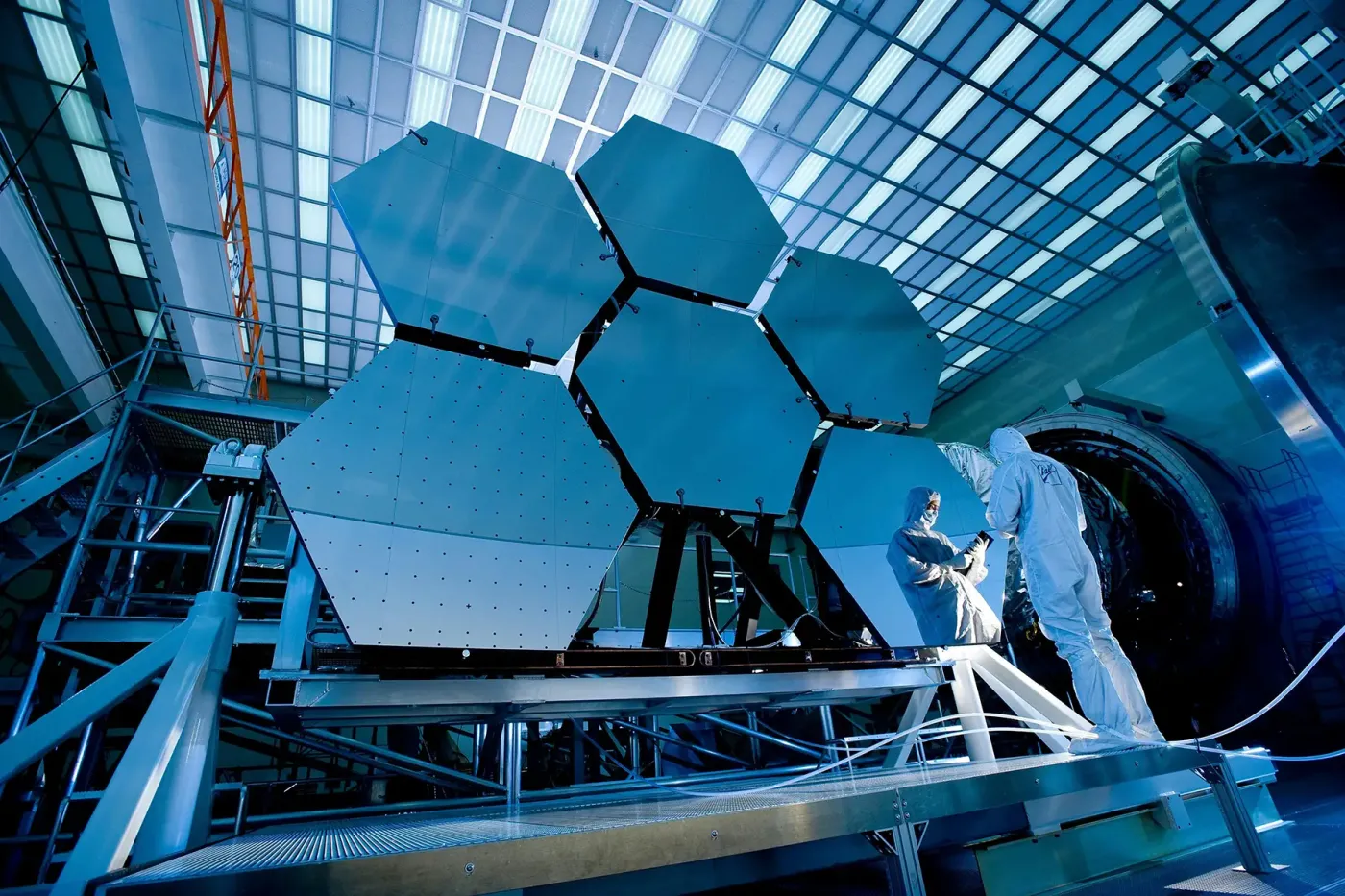 Engineers in cleanroom suits inspect aerospace components in a high-tech lab, illustrating precision gas systems for spacecraft and satellite applications.