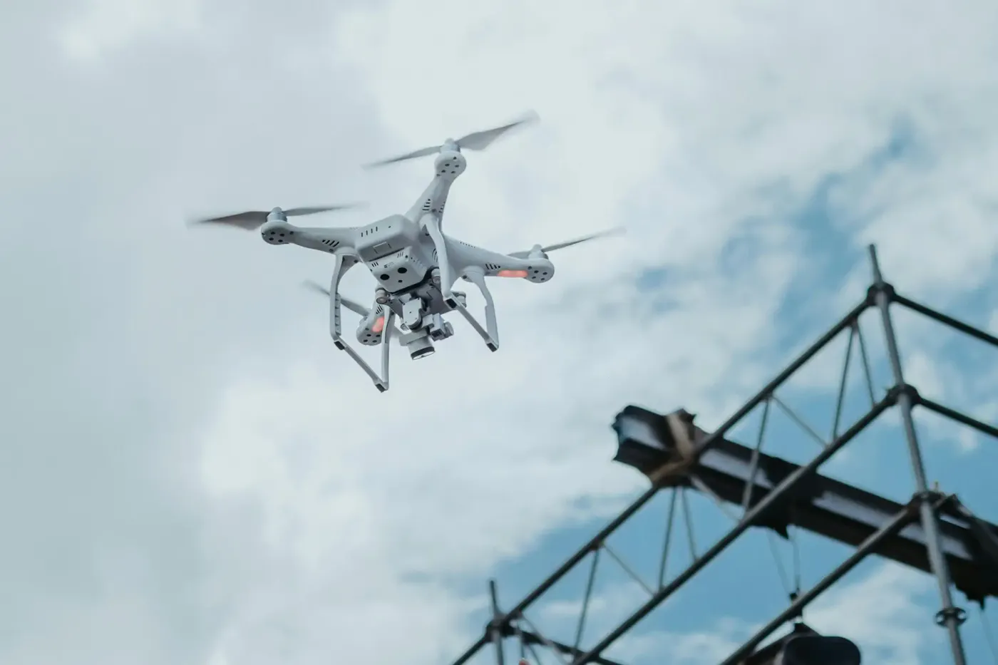 Quadcopter drone flying near industrial scaffolding, representing lightweight energy storage applications for robotics, UAVs, and high-performance field equipment.
